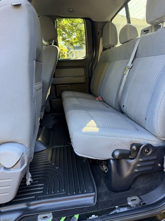Clean gray rear bench seat and black floor mats in the back of the cab