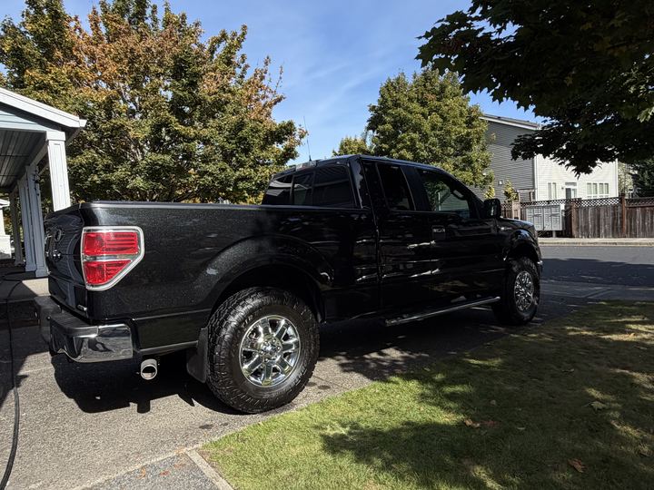 Rear three-quarter view of the black truck shining in the sun